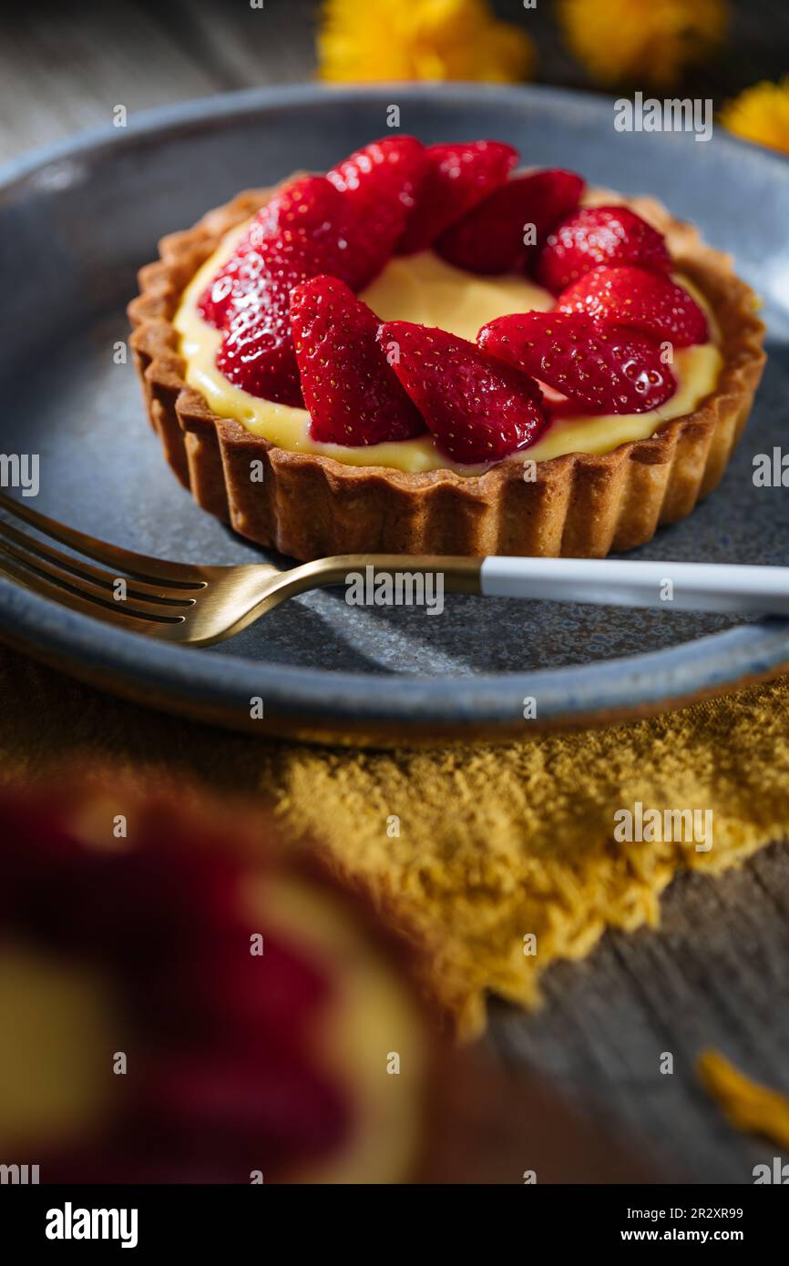 Erdbeertörtchen, französisches Dessert auf einem rustikalen Holztisch in einer dramatischen dunklen Szene Stockfoto