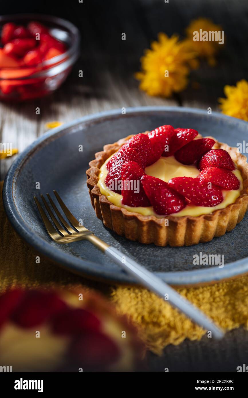 Erdbeertörtchen, französisches Dessert auf einem rustikalen Holztisch in einer dramatischen dunklen Szene Stockfoto