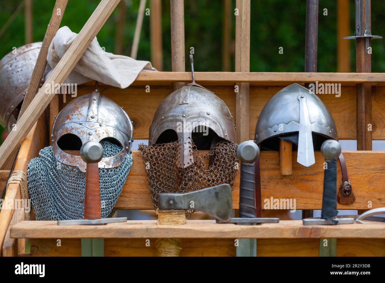 Helme, Schwerter und andere Kriegswaffen aus dem Mittelalter auf einem Holzständer. Stockfoto
