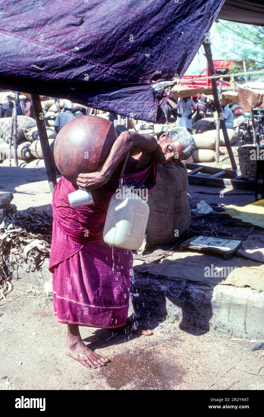 Eine alte Frau, die Trinkwasser aus dem Topf in eine Dose füllt, wöchentlicher Zeitschriftenmarkt in Pollachi, Tamil Nadu, Südindien, Indien, Asien Stockfoto