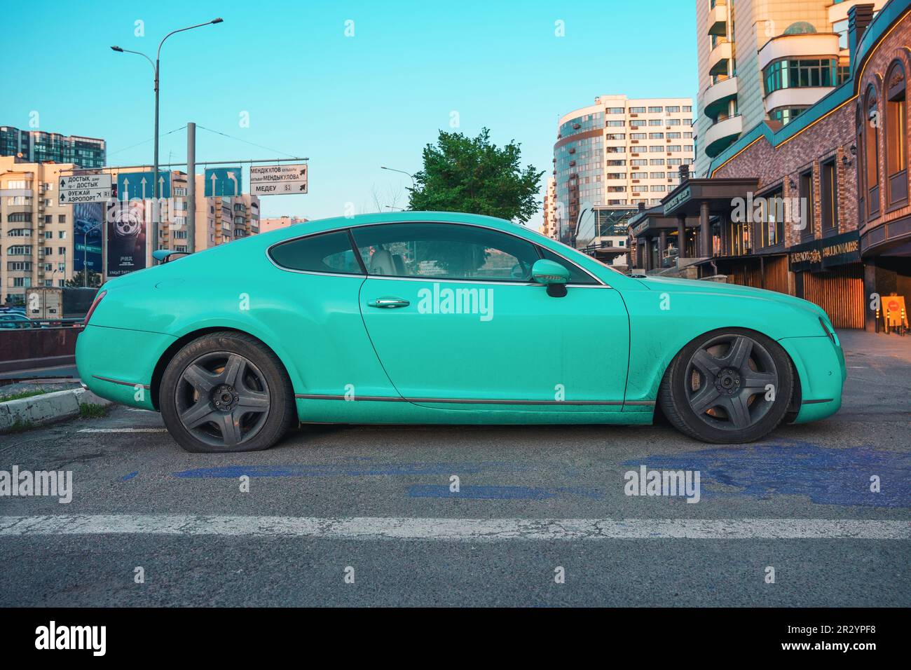 Almaty, Kasachstan - 4. Mai 2023: Ein Bentley Continental GT wird mit einem Platten Hinterreifen geparkt. Türkisfarbene Karosserie Stockfoto