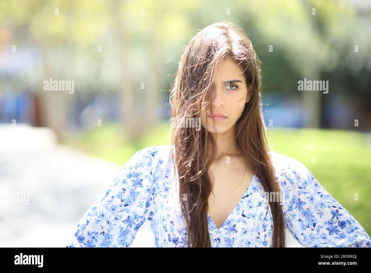 Wütende Frau mit touseltem Haar, ein windiger Tag, der auf der Straße in die Kamera schaut Stockfoto