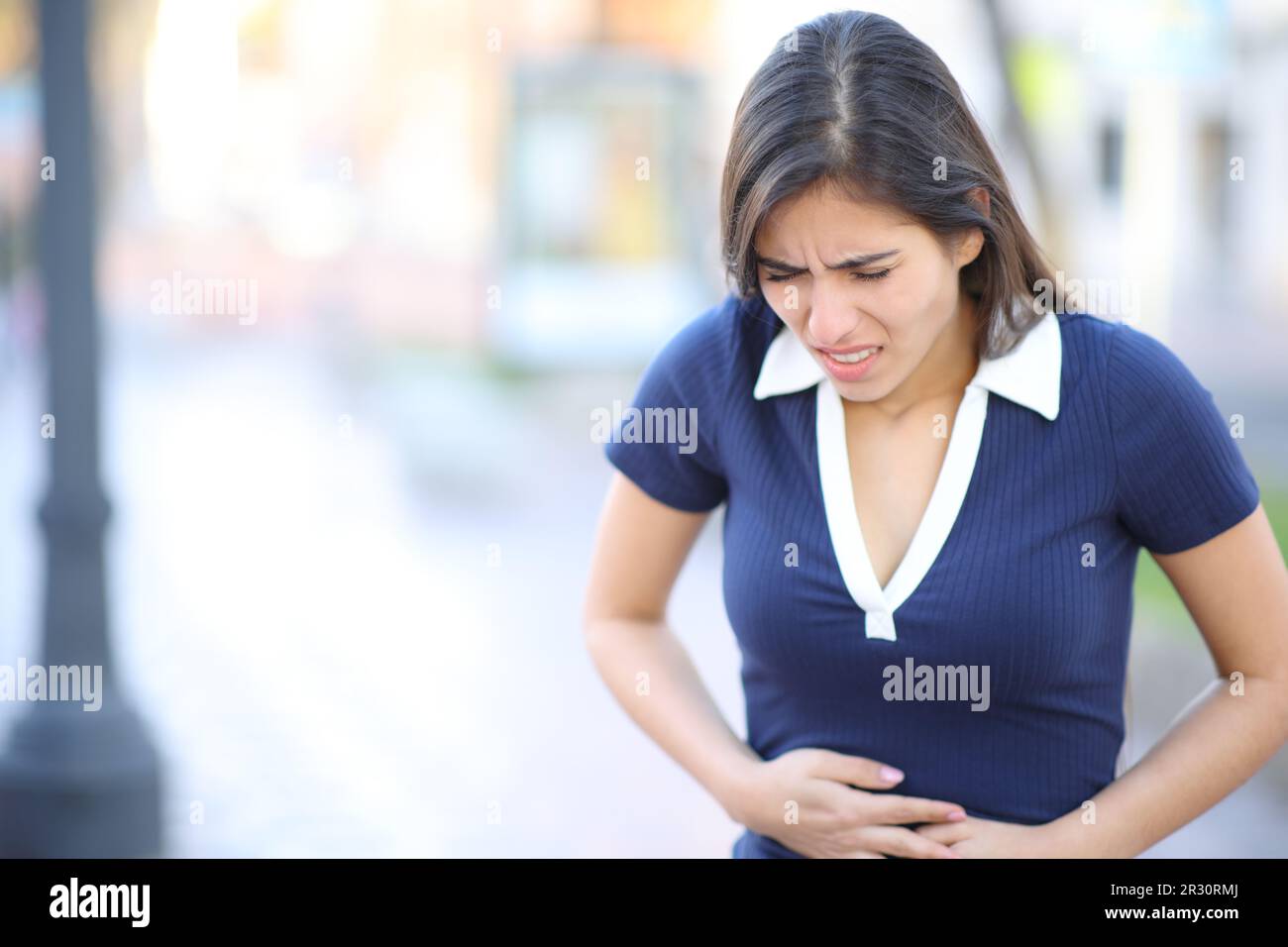Frau mit Bauchschmerzen, die auf der Straße läuft Stockfoto