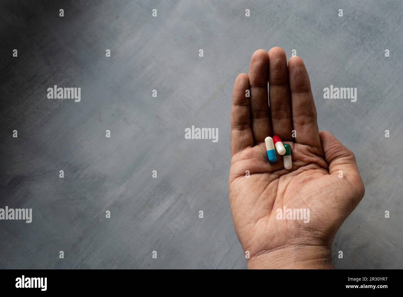 Bunte Medizinpillen in der Hand mit Textbereich. Medizin- und Gesundheitskonzept Stockfoto