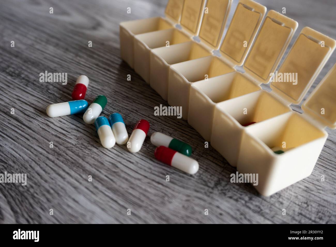 Nahaufnahme von bunten Medizinpillen und Pillbox-Organisator auf Tisch mit Platz für Text Stockfoto