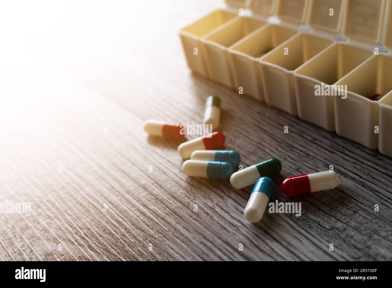 Nahaufnahme von bunten Medizinpillen und Pillbox-Organisator auf Tisch mit Platz für Text Stockfoto