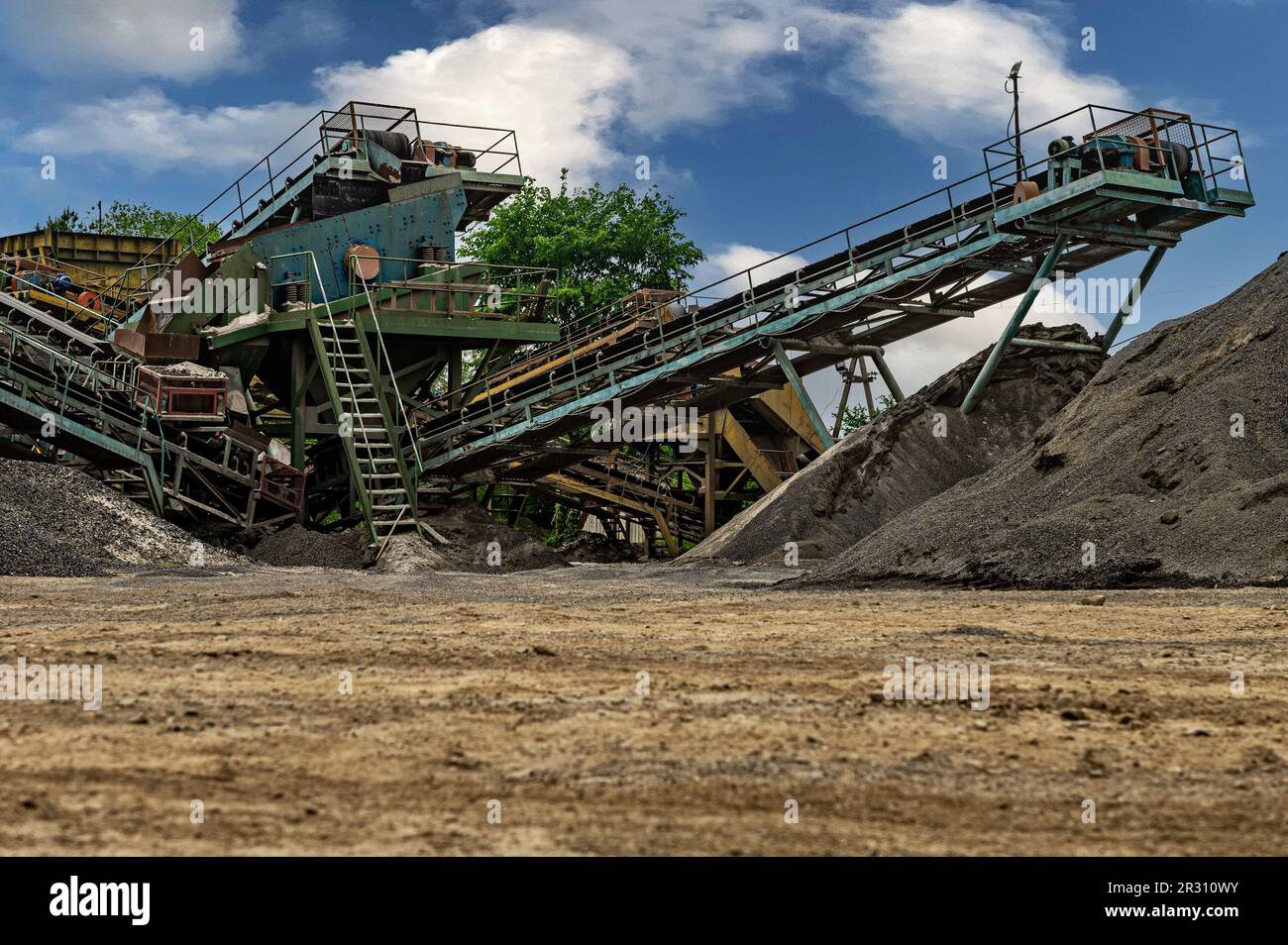 Steinbruchförderer für die Minningindustrie. Brechmaschinen, Kegelsteinbrecher, Förderer von zerdrücktem Granitkiesstein in einem Steinbruch-Minin Stockfoto