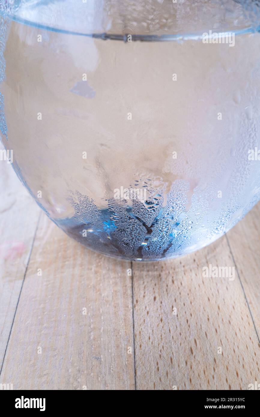 Eine Nahaufnahme des Kondensats an der Seite einer Glaskanne mit Wasser auf einem Tisch. Stockfoto