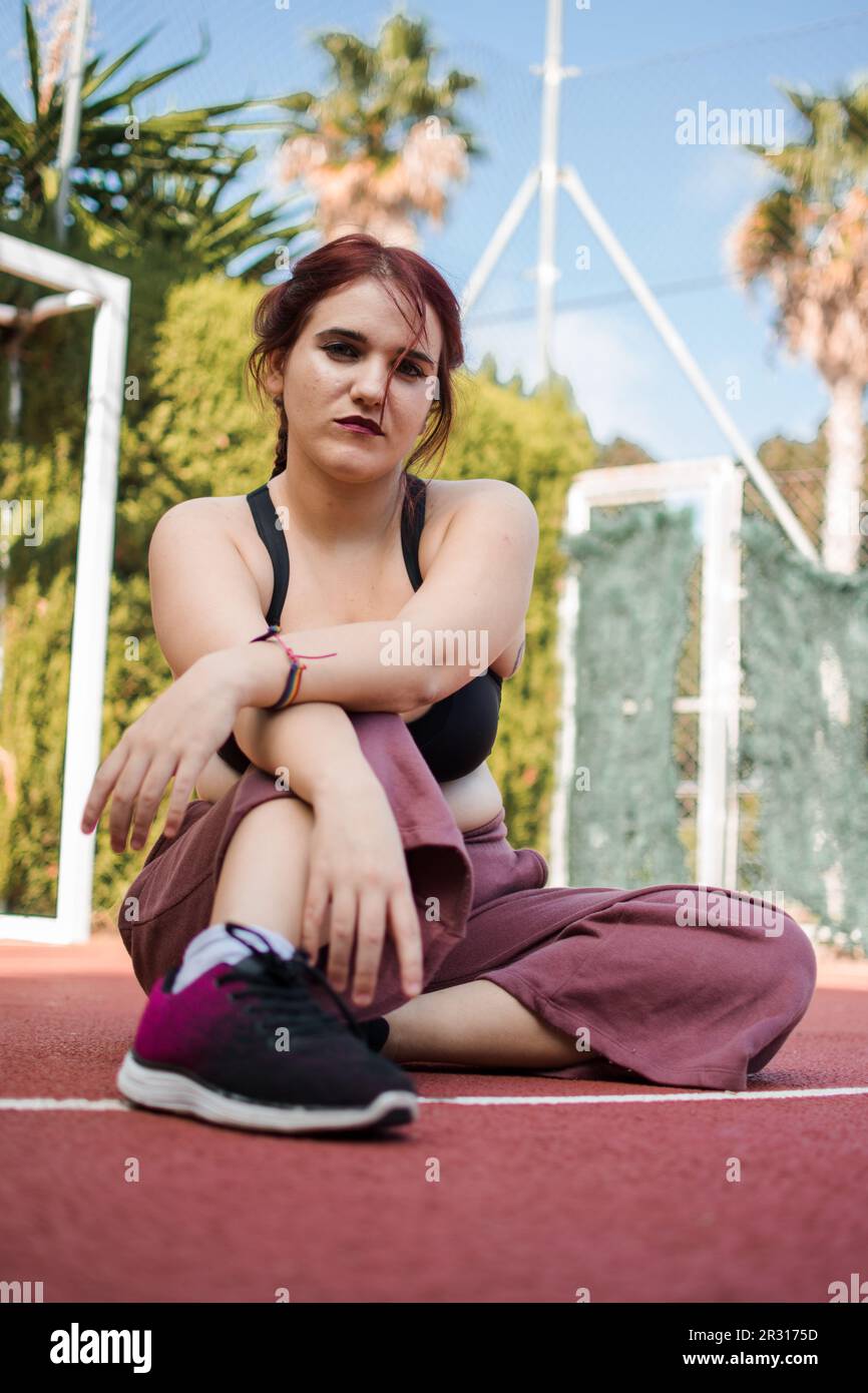 Eine junge Frau, die mit städtischen Klamotten posiert, ist ein Basketballfeld Stockfoto