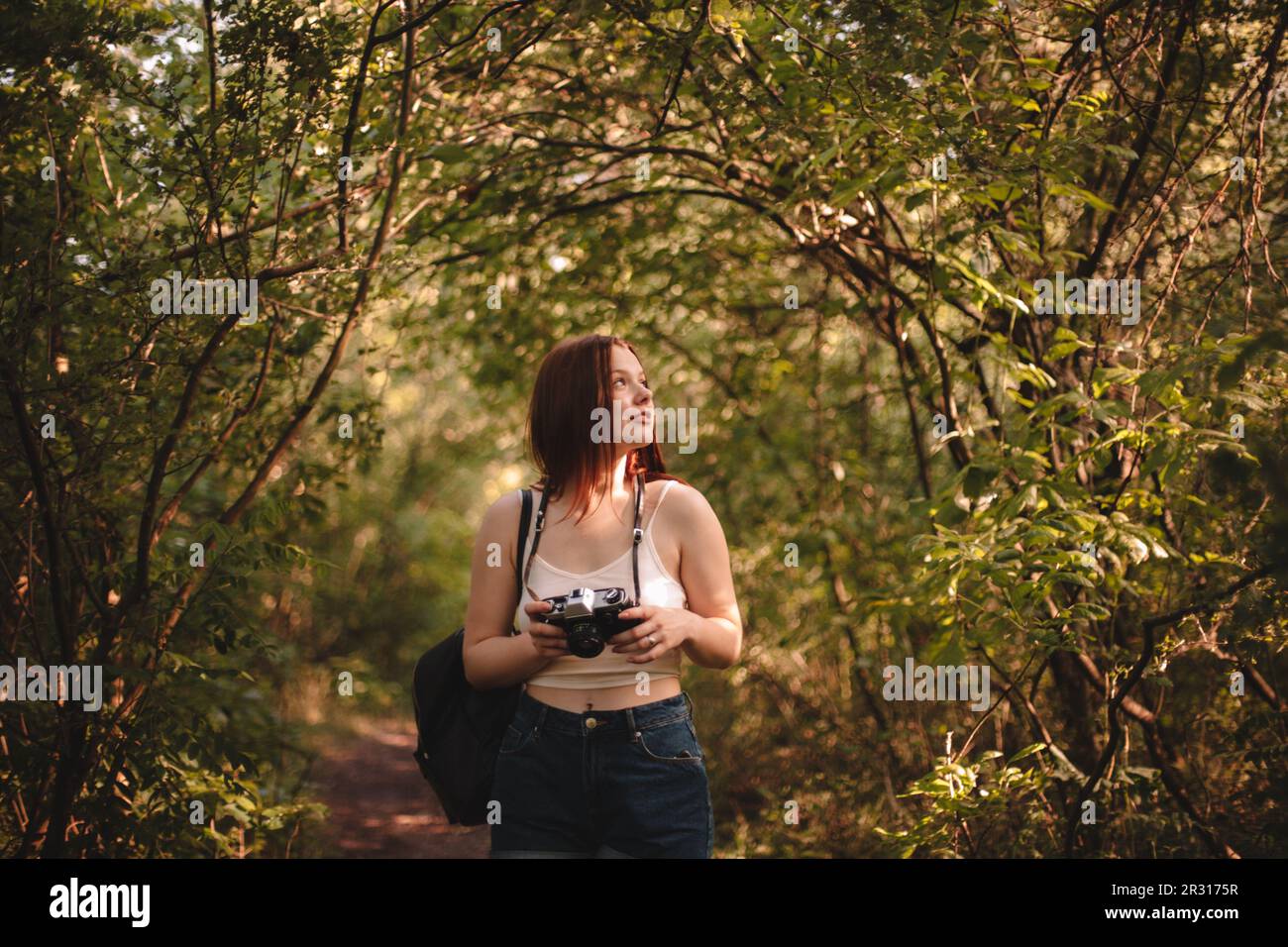 Weibliche Touristin, die im Sommer im Wald eine Kamera hält Stockfoto