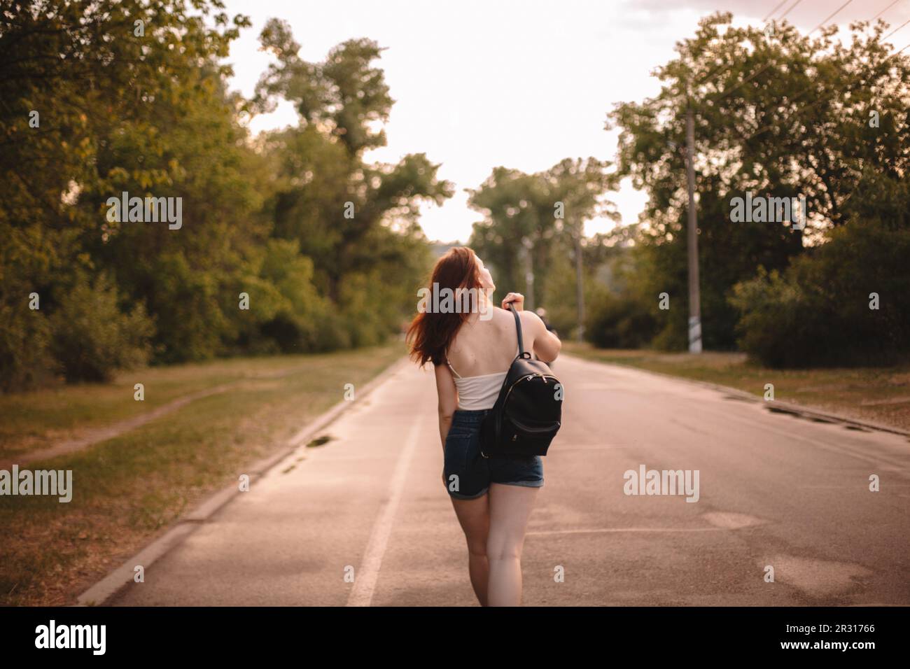Rückansicht einer jungen Frau, die im Sommer auf der Landstraße unterwegs ist Stockfoto