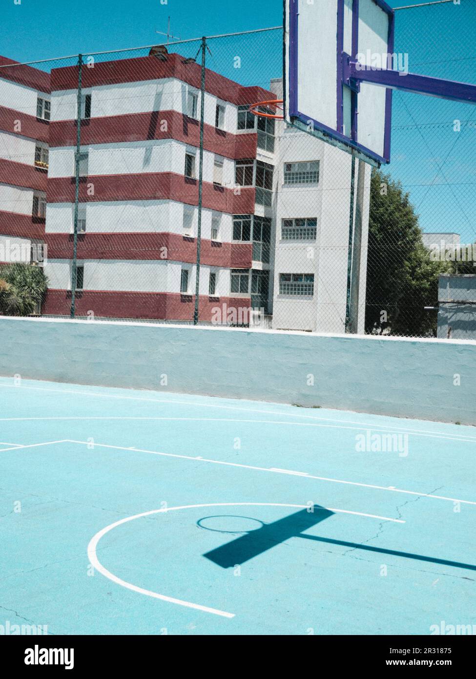 Basketballtor auf blauem Platz vor bunten Gebäuden Stockfoto