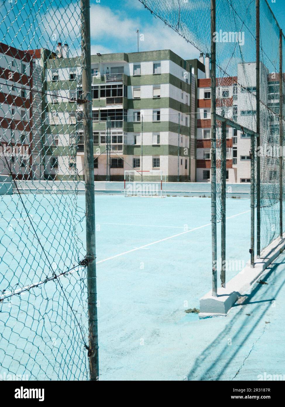 Farbenfrohe Gebäude und blauer Platz durch das Tor am Ballstopp-Zaun Stockfoto