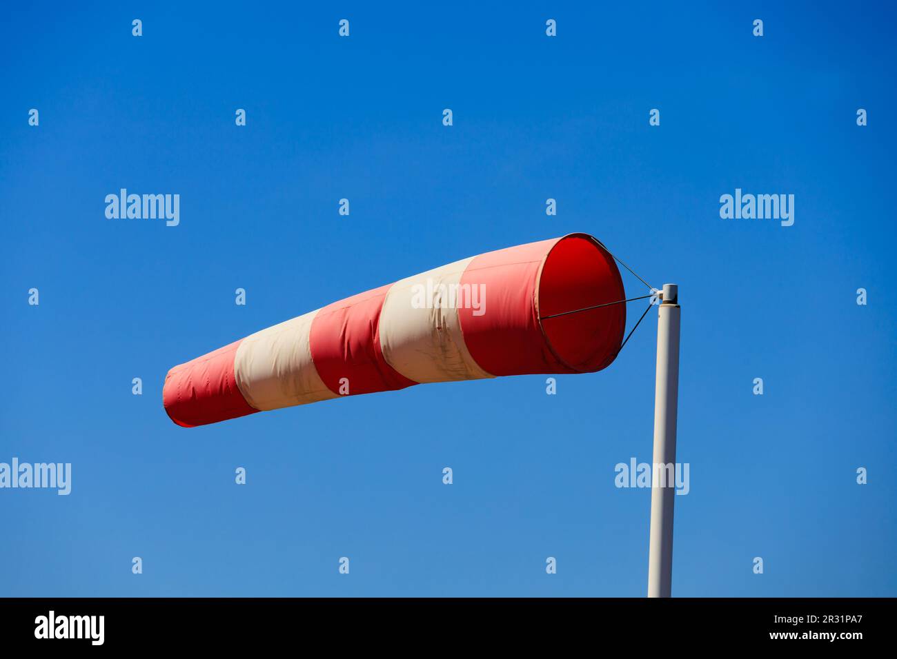 Rot-weiße Windsocken mit hoher Windstärke und klarem blauem Himmel. Stockfoto