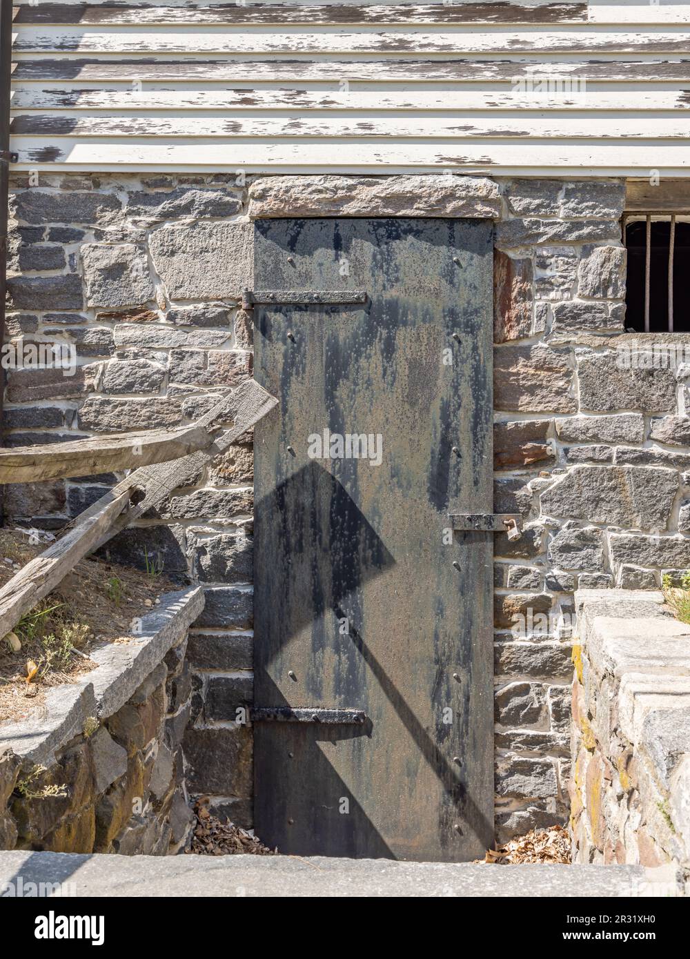 Alte schwarze Metalltür im Untergeschoss eines Wohnhauses in einem Hafen Stockfoto