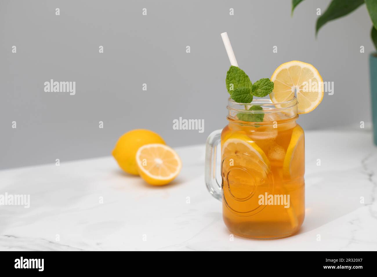 Ein Glas kalten Tee, Eiswürfel, Zitronenscheiben und einen Pfefferminzzweig. Kühle Sommergetränke. Stockfoto