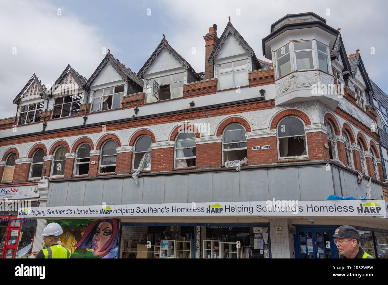 Westcliff on Sea, Großbritannien. Mai 2023. Mehrstöckiges Gebäude mit HARFE, Southends Obdachlosenhilfe, mit Renovierungsarbeiten. Bauarbeiter in hochsichtbarer Ausrüstung im Vordergrund sichtbar. Überreste eines dreistöckigen Gebäudebrandes in der Nähe der Hamlet Court Road. Das Gebäude wurde am Abend des 21. Mai in Brand gesetzt. In der Höhe des Feuers waren acht Mannschaften mit zwei Hubleiter-Plattformen und einer Vorfallskommando anwesend. Die Feuerwehrleute blieben über Nacht auf dem Gelände, und die örtlichen Straßen bleiben gesperrt. Penelope Barritt/Alamy Live News Stockfoto
