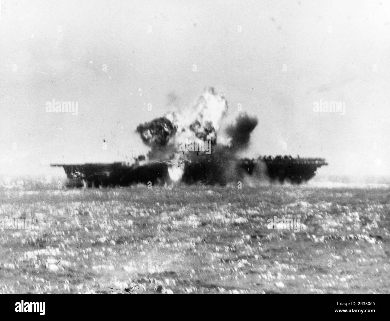 Ein bemerkenswertes Foto, das zeigt, wie die USS Essex von einem Kamikaze östlich von Luzon, Philippinen, getroffen wird, 25. November 1944. Japan stand Ende 1944 vor einer Niederlage und entschied sich, US-Schiffe mit Selbstmordattentaten, Kamikaze genannt, zu zerstören. Diese Angriffe waren eine starke physische und psychologische Waffe und versenkten insgesamt 47 Schiffe zu einem Preis von mehr als 3000 Piloten und Flugzeugen. Ende 1944 war die US-Marine so groß, dass die Verluste unbedeutend waren und den Verlauf des Krieges nicht veränderten. Stockfoto