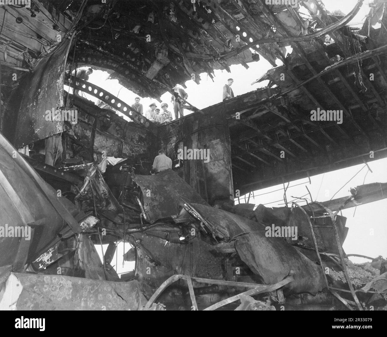 Seeleute, die den Schaden sehen, der dem Flugzeugträger USS Randolph durch einen japanischen Kamikaze-Angriff zugefügt wurde. Als Japan Ende 1944 mit einer Niederlage konfrontiert war, entschied es sich, US-Schiffe mit Selbstmordattentaten, bekannt als Kamikaze, zu zerstören. Diese Angriffe waren eine starke physische und psychologische Waffe und versenkten insgesamt 47 Schiffe zu einem Preis von mehr als 3000 Piloten und Flugzeugen. Ende 1944 war die US-Marine so groß, dass die Verluste unbedeutend waren und den Verlauf des Krieges nicht veränderten. Stockfoto