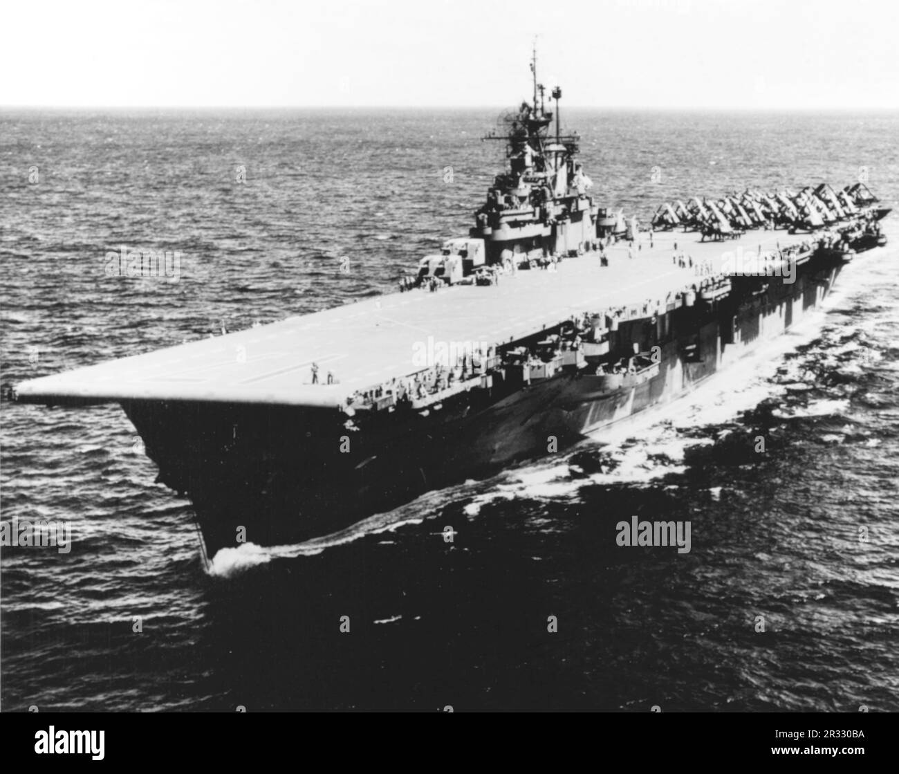 Der US-Flugzeugträger der Essex-Klasse USS Bunker Hill (CV-17) auf See im Jahr 1945. Das Schiff wurde am 11. Mai 1945 in Okinawa durch zwei Kamikaze-Angriffe in einer Minute schwer beschädigt. Er griff voll betankt und bewaffnete Flugzeuge an Deck an und löste sehr gefährliche Brände aus. Obwohl das Schiff schwer beschädigt war, ging es nicht unter und kehrte zur Reparatur in die USA zurück. Das Schiff wurde 1966 stillgelegt und 1973 verschrottet. Stockfoto