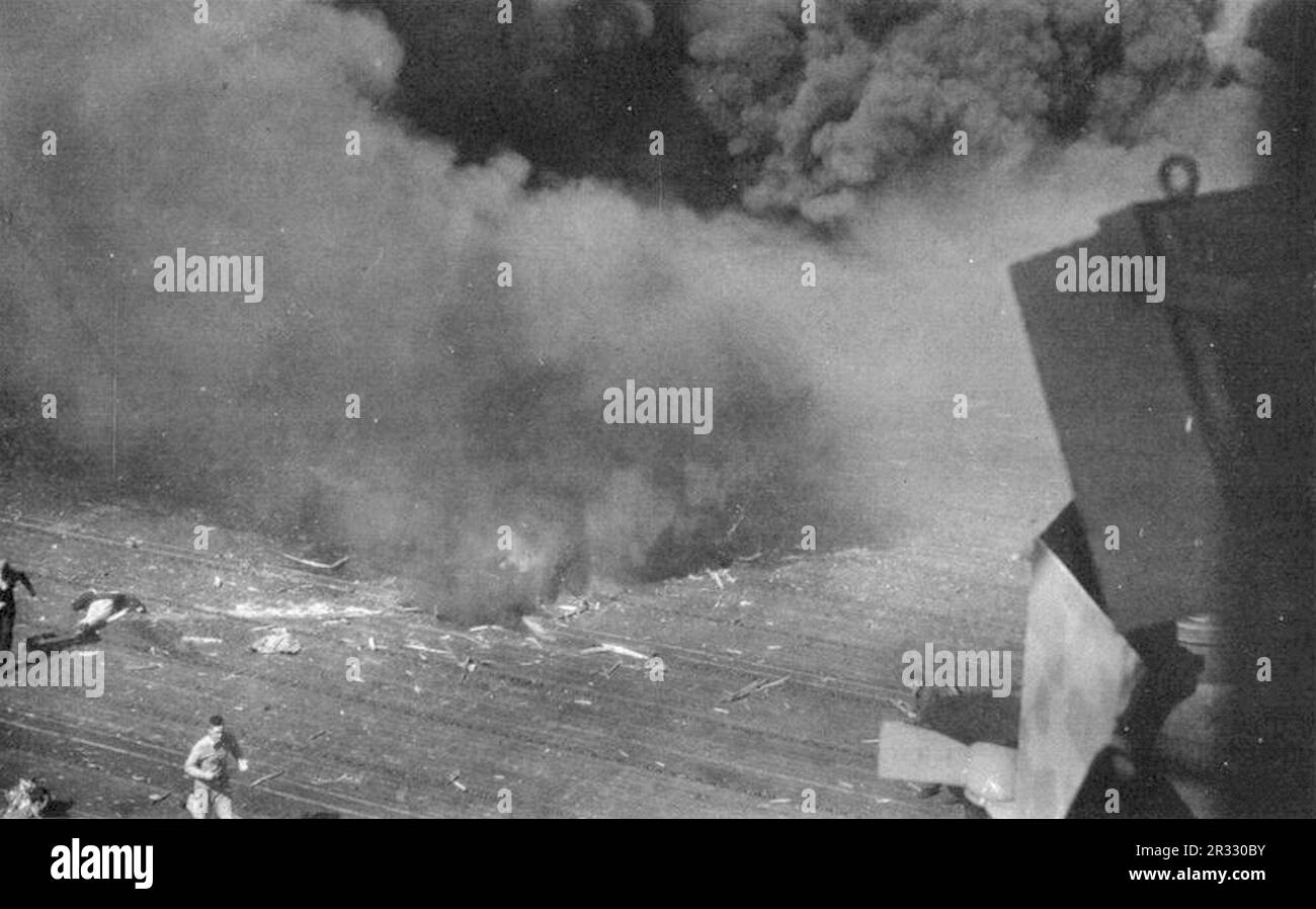 Rauch strömt aus einem Loch im Flugdeck der USA Navy Aircraft Carrier USS Ticonderoga (CV-14) nach einem Anschlag von einem japanischen Kamikaze am 21. Januar 1945. Als Japan Ende 1944 mit einer Niederlage konfrontiert war, entschied es sich, US-Schiffe mit Selbstmordattentaten, bekannt als Kamikaze, zu zerstören. Diese Angriffe waren eine starke physische und psychologische Waffe und versenkten insgesamt 47 Schiffe zu einem Preis von mehr als 3000 Piloten und Flugzeugen. Ende 1944 war die US-Marine so groß, dass die Verluste unbedeutend waren und den Verlauf des Krieges nicht veränderten. Stockfoto