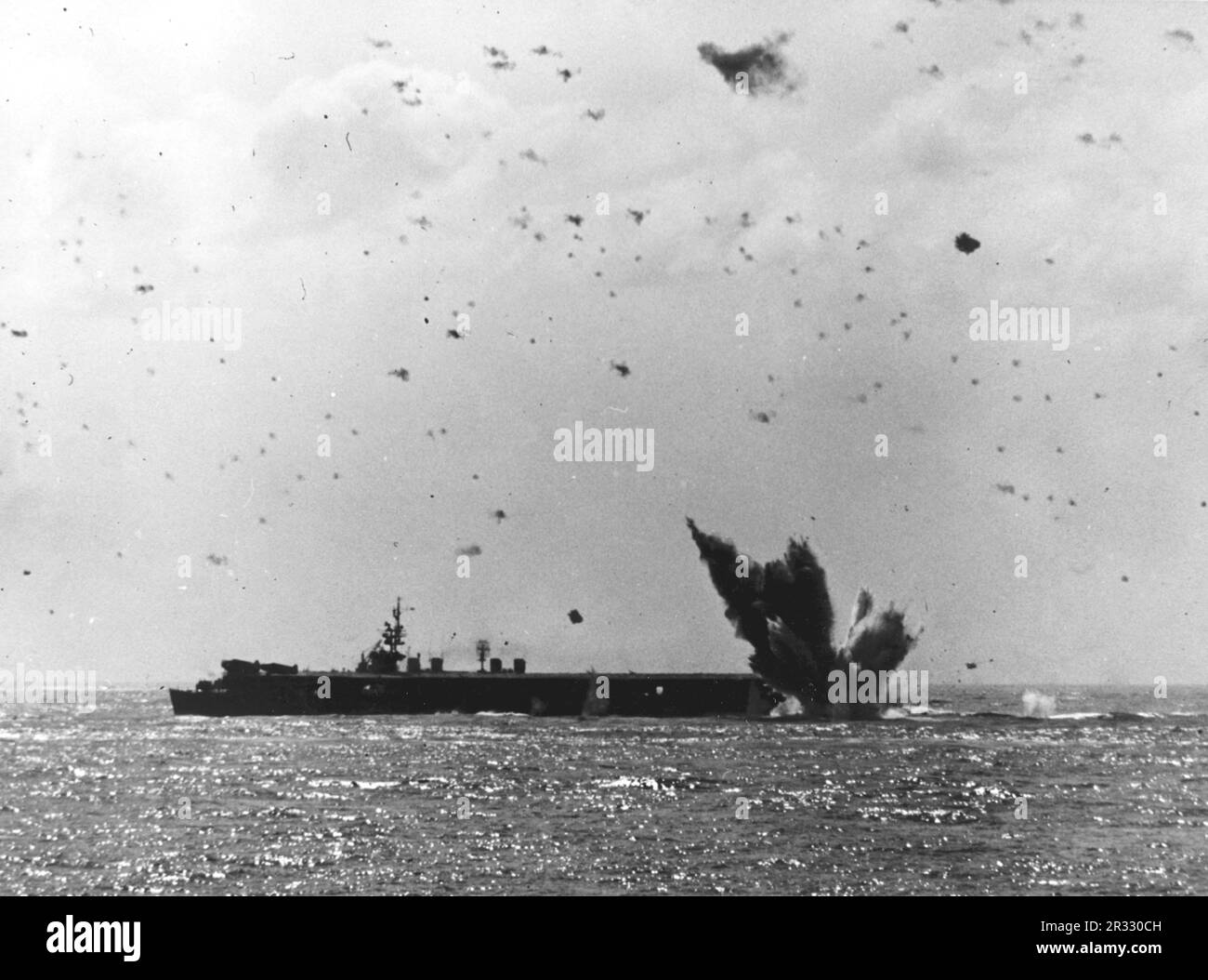 Ein japanisches Flugzeug stürzt in der Nähe des Hecks eines US-Flugzeugs ab Navy Light Aircraft Carrier, während eines erfolglosen Kamikaze-Angriffs am 17. April 1945. Da das Foto vom Schlachtschiff USS South Dakota (BB-57) aufgenommen wurde, ist der Träger höchstwahrscheinlich USS Bataan Stockfoto