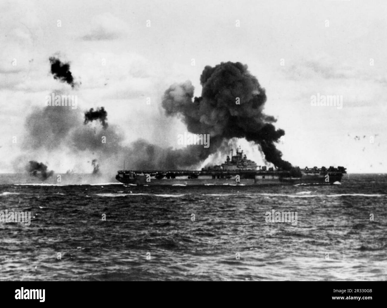 Die USA Der Flugzeugträger USS Intrepid (CV-11) der Marine brannte, nachdem das Schiff von zwei japanischen Kamikaze-Flugzeugen getroffen wurde, am 16. April 1945. Als Japan Ende 1944 mit einer Niederlage konfrontiert war, entschied es sich, US-Schiffe mit Selbstmordattentaten, bekannt als Kamikaze, zu zerstören. Diese Angriffe waren eine starke physische und psychologische Waffe und versenkten insgesamt 47 Schiffe zu einem Preis von mehr als 3000 Piloten und Flugzeugen. Ende 1944 war die US-Marine so groß, dass die Verluste unbedeutend waren und den Verlauf des Krieges nicht veränderten. Stockfoto