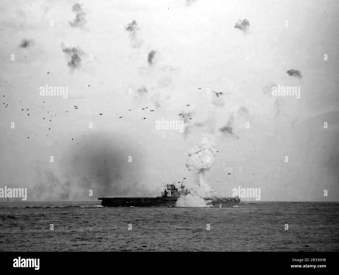 Die USA Der Flugzeugträger USS Enterprise (CV-6) der Marine wurde am 14. Mai 1945 von einem japanischen bombenbeladenen Kamikaze getroffen. Der Fahrstuhl des Schiffs wurde etwa 400 Meter hoch in die Luft gesprengt, durch die Kraft der Explosion, sechs Decks darunter. Als Japan Ende 1944 mit einer Niederlage konfrontiert war, entschied es sich, US-Schiffe mit Selbstmordattentaten, bekannt als Kamikaze, zu zerstören. Diese Angriffe waren eine starke physische und psychologische Waffe und versenkten insgesamt 47 Schiffe zu einem Preis von mehr als 3000 Piloten und Flugzeugen. Ende 1944 war die US-Marine so groß, dass die Verluste unbedeutend waren und sich nicht änderten Stockfoto