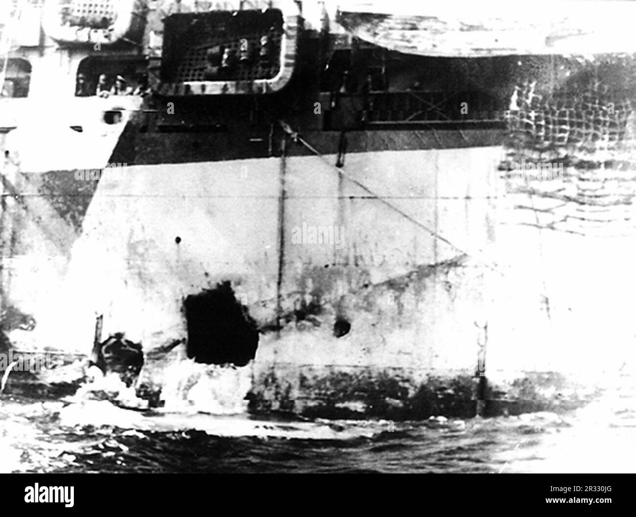 Blick auf den Kamikaze-Schaden der USA Marine-Angriffstransport USS Hinsdale (APA-120). Sie wurde am 1. April 1945 von einer Kawasaki Ki-61 aus Okinawa, Japan, getroffen. Das sichtbare Loch ist auf der Backbordseite mittschiffs. Als Japan Ende 1944 mit einer Niederlage konfrontiert war, entschied es sich, US-Schiffe mit Selbstmordattentaten, bekannt als Kamikaze, zu zerstören. Diese Angriffe waren eine starke physische und psychologische Waffe und versenkten insgesamt 47 Schiffe zu einem Preis von mehr als 3000 Piloten und Flugzeugen. Ende 1944 war die US-Marine so groß, dass die Verluste unbedeutend waren und den Verlauf des Krieges nicht veränderten. Stockfoto