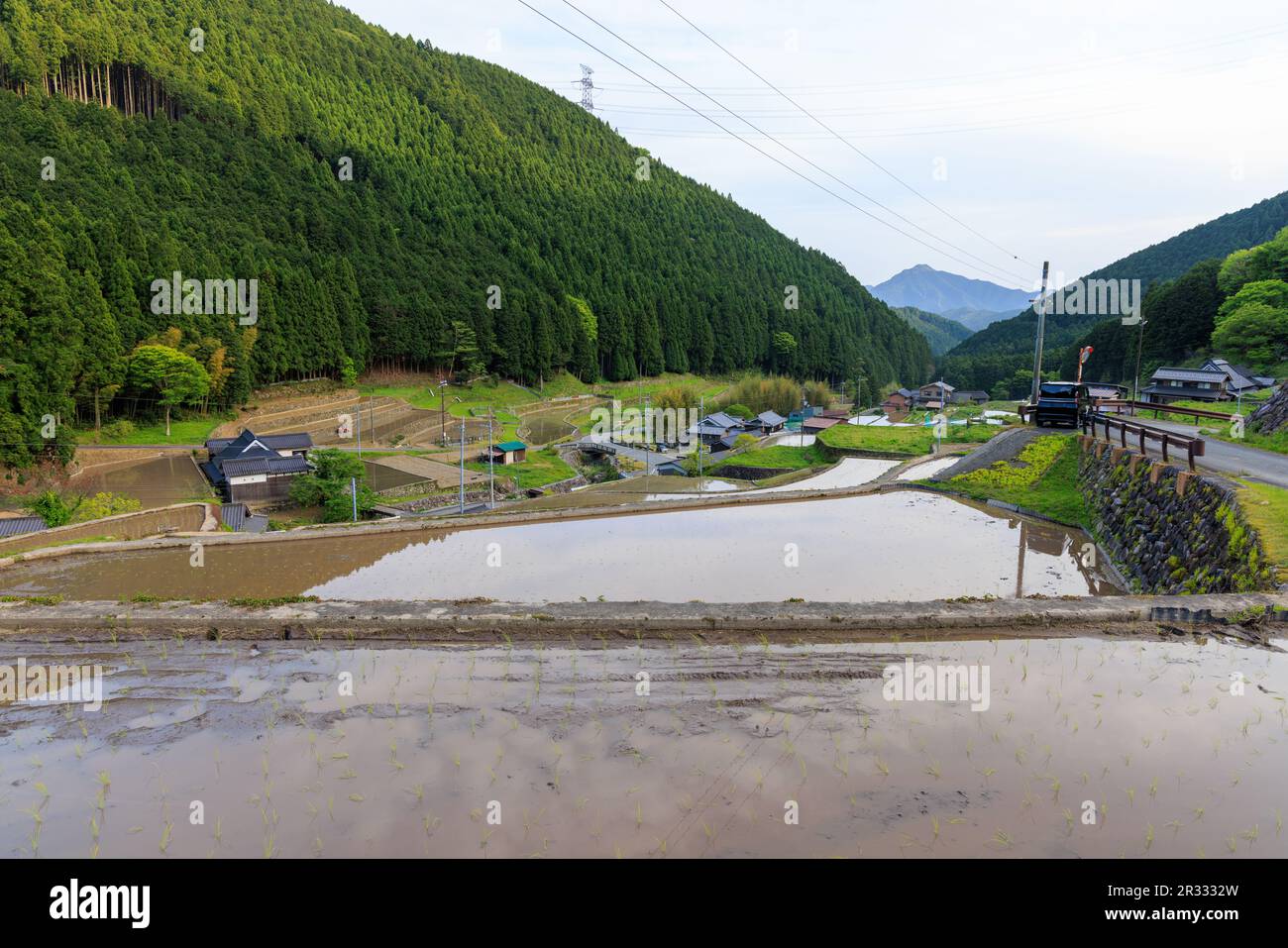 Terrassenförmig angelegte Reisfelder bieten einen Blick auf ein kleines Dorf in einer Berglandschaft Stockfoto