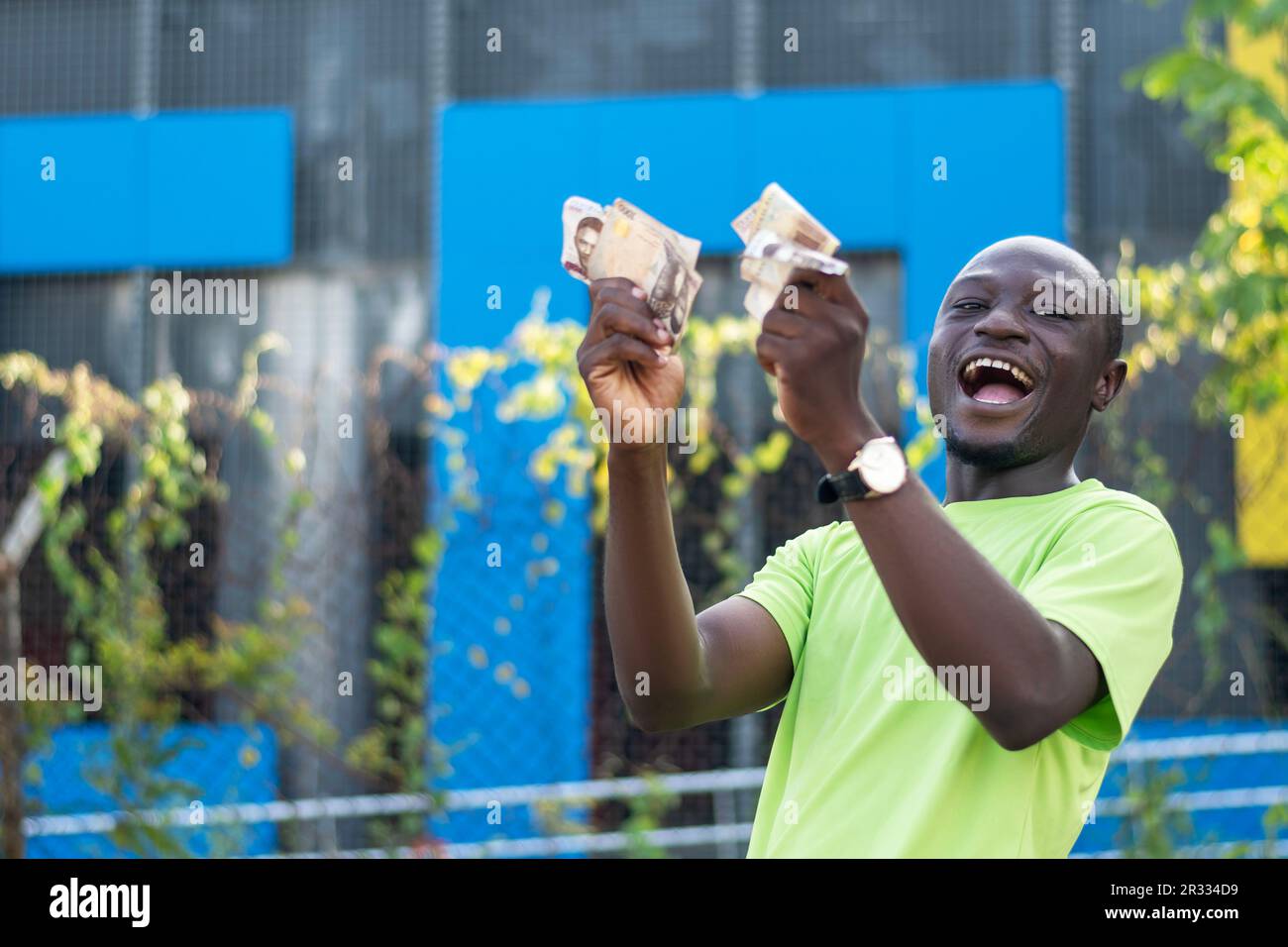 Foto eines Afrikaners, der stolz einen Haufen Bargeld in seiner Hand zeigt Stockfoto