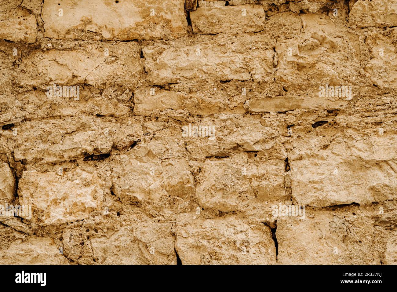 Horizontale Struktur der alten Wand aus grobem braunem Sandstein, mit gebrochenem alten Putz aus Ton Stockfoto