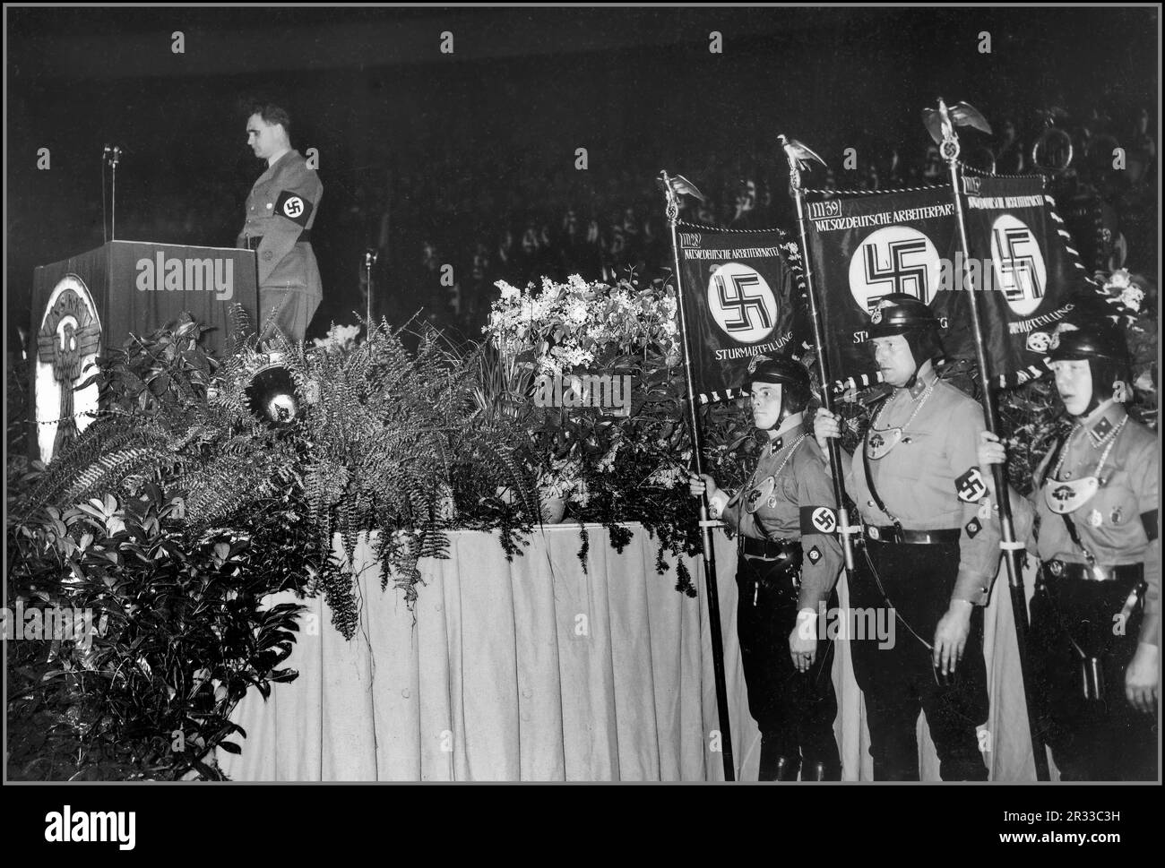 PROPAGANDAFOTO VON RUDOLF HESS, aufgenommen am 16. Januar 1936 bei der Generalversammlung des Nationalen Sozialistischen Kraftfahrkorps (NSKK) in der Deutschlandhalle-Arena in Berlin, Nazideutschland. Rede von Rudolf Hess. Standardarbeiter/Ehrengäste des NSKK in Uniformen, die eng an denen der Sturmabteilung (SA) orientieren, zu der der NSKK ursprünglich gehörte. Berliner Nazideutschland Stockfoto