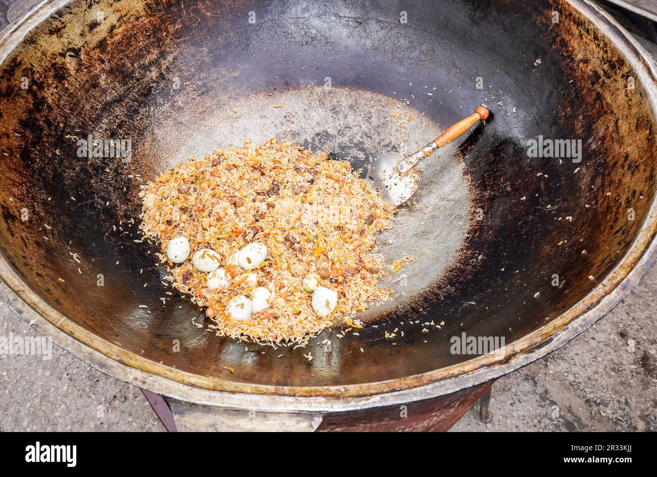 Appetitlich traditioneller Usbekischer Pilaw in einem großen Kessel im Freien Stockfoto
