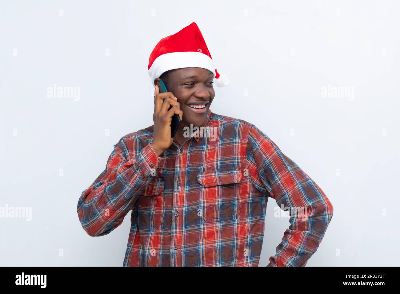 Junger afrikanischer Mann in santa hat, der das Telefon isoliert auf weißem Hintergrund hält Stockfoto