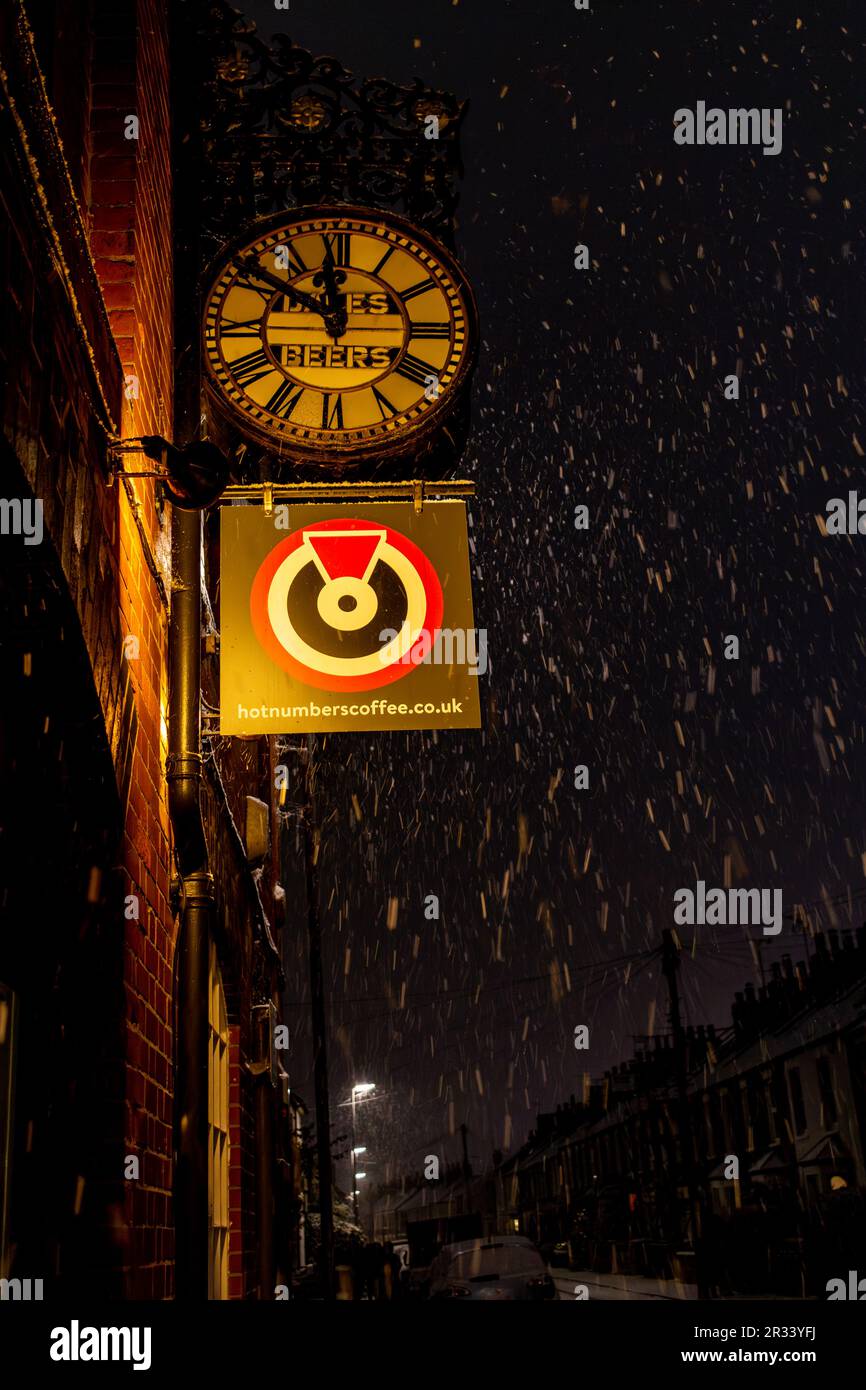 Das Schild für Hot Numbers Cafe erstrahlt an einer verschneiten Winternacht auf der Gwydir Street, Cambridge, Großbritannien Stockfoto