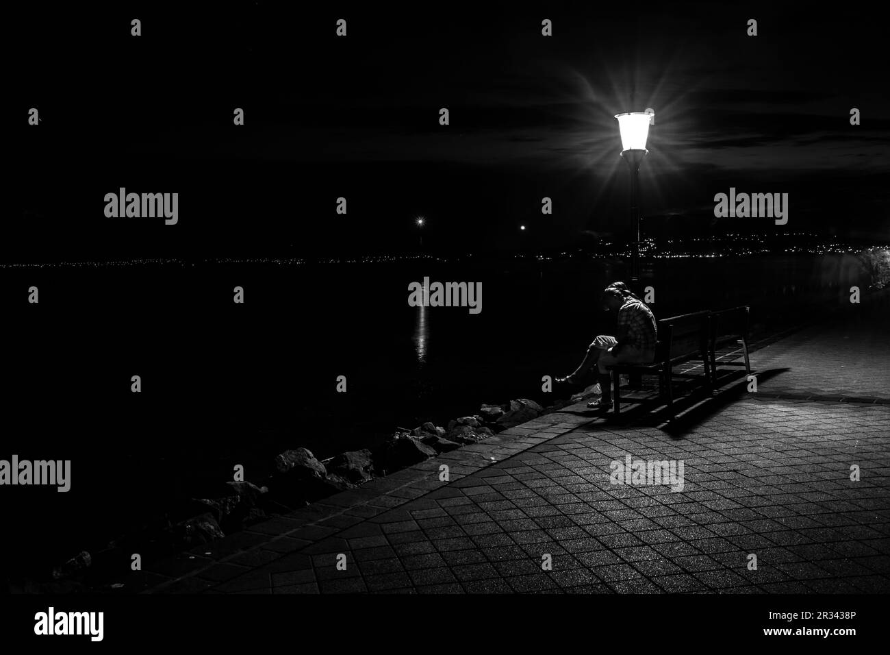 Ein Mann sitzt nachts allein auf einer Bank Stockfoto