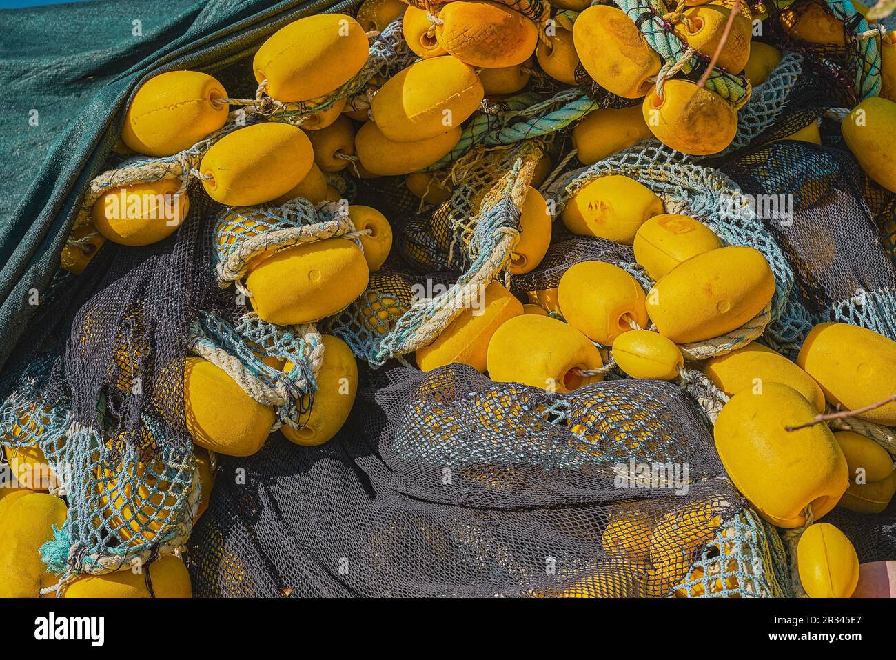 Fischernetze mit gelben Schwimmern am Pier, Nahaufnahme, selektiver Fokus. Hintergrund des Konzepts der industriellen Fischerei Stockfoto
