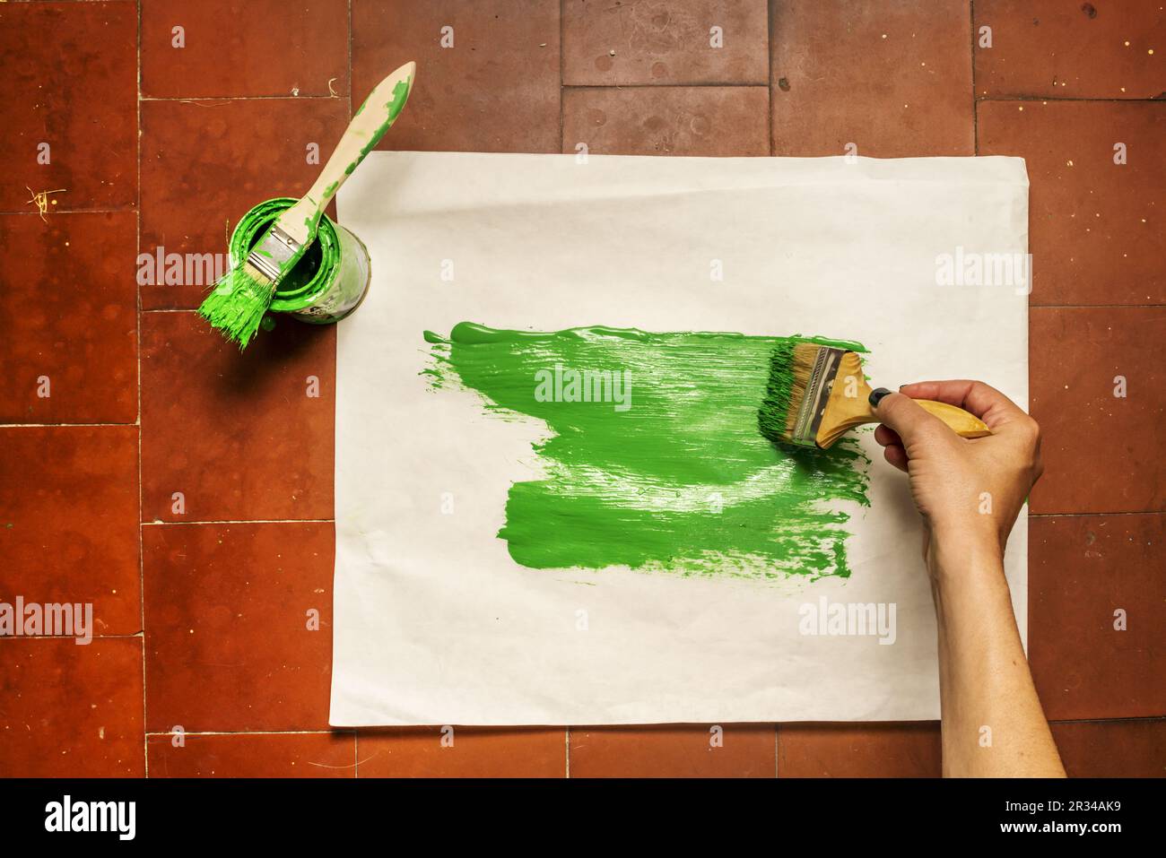 Lackierung eines Papierstapels mit einem Topf grüner synthetischer Emailfarbe mit verschiedenen Pinseln Stockfoto