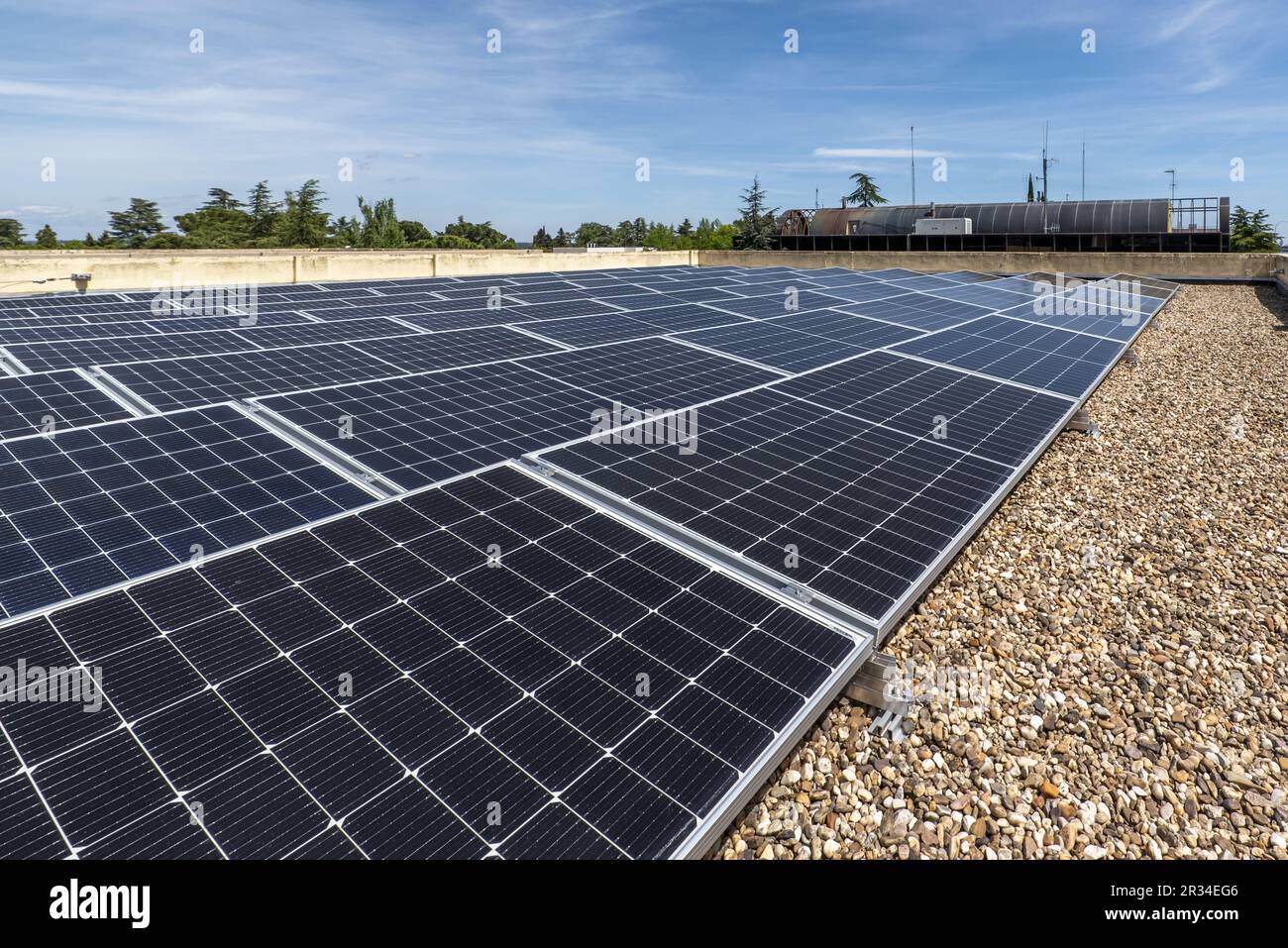 Das Dach eines Bürogebäudes ist mit Kies bedeckt, auf dem ein Haufen Sonnenkollektoren befestigt sind, die sich nicht an der heißesten Sonne orientieren können Stockfoto