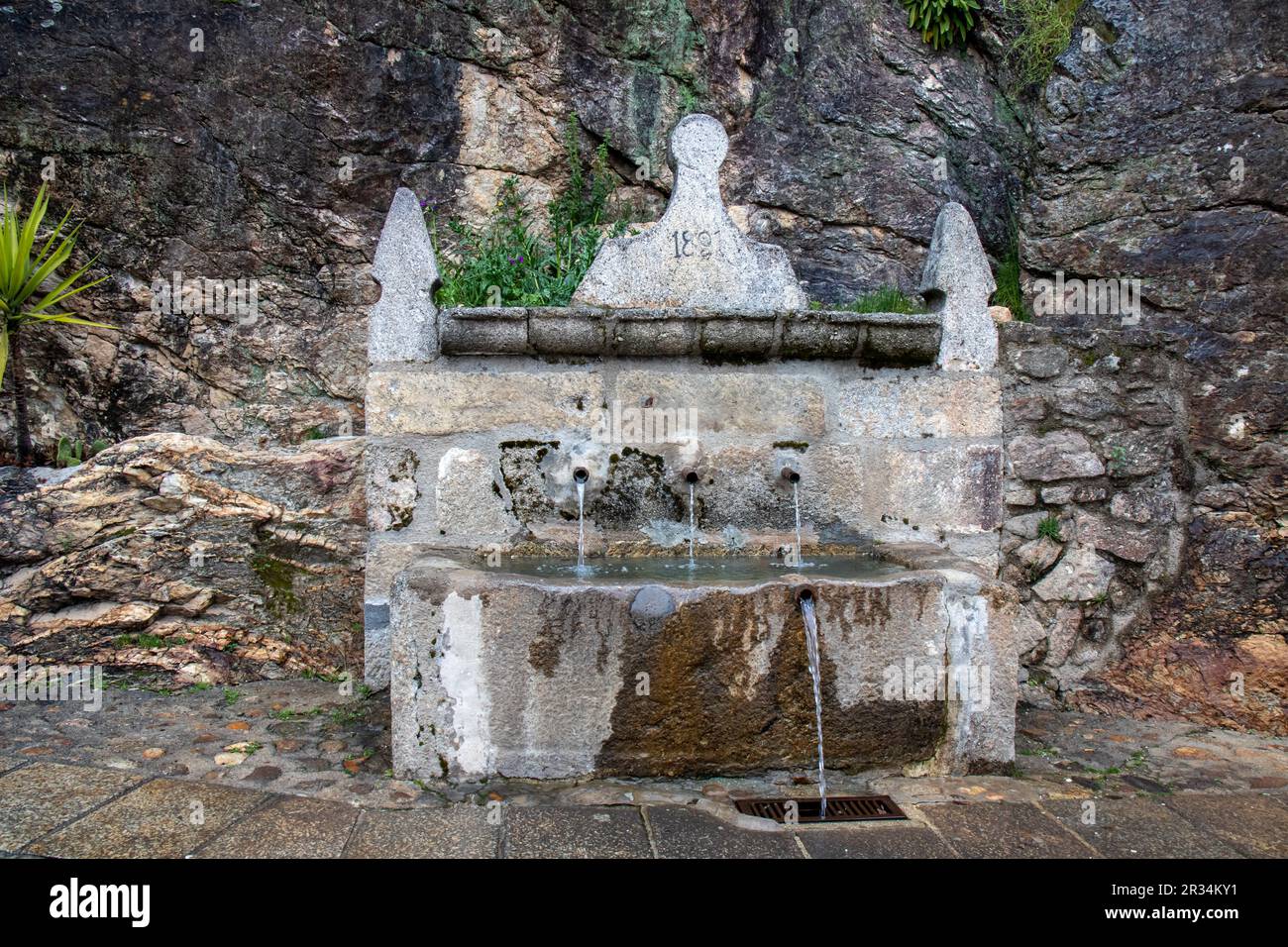 Fuente de la higuera, con tres chorros, adosada a una enorme roca, en el bonito pueblo de Cuacos de Yuste, Cáceres, España Stockfoto