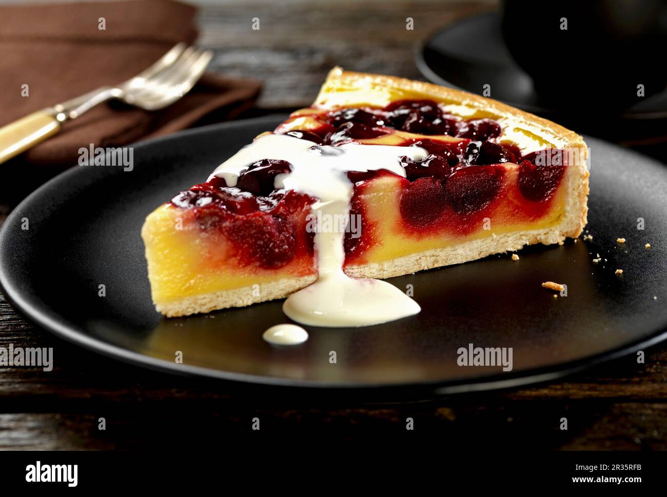 Eine Scheibe Pudding-Tarte mit Kirsche und Vanille und Rahm Stockfoto