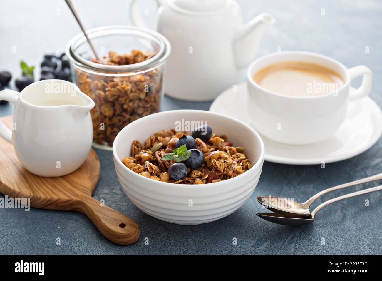 Hausgemachtes Müsli mit Milch zum Frühstück serviert mit Kaffee Stockfoto