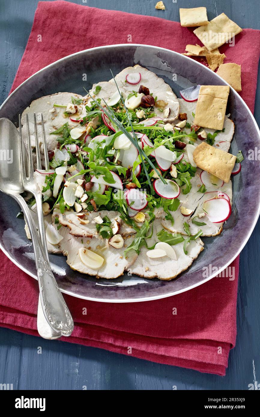 Kalbfleisch-Carpaccio mit Radieschen, Rucola und Haselnüssen Stockfoto