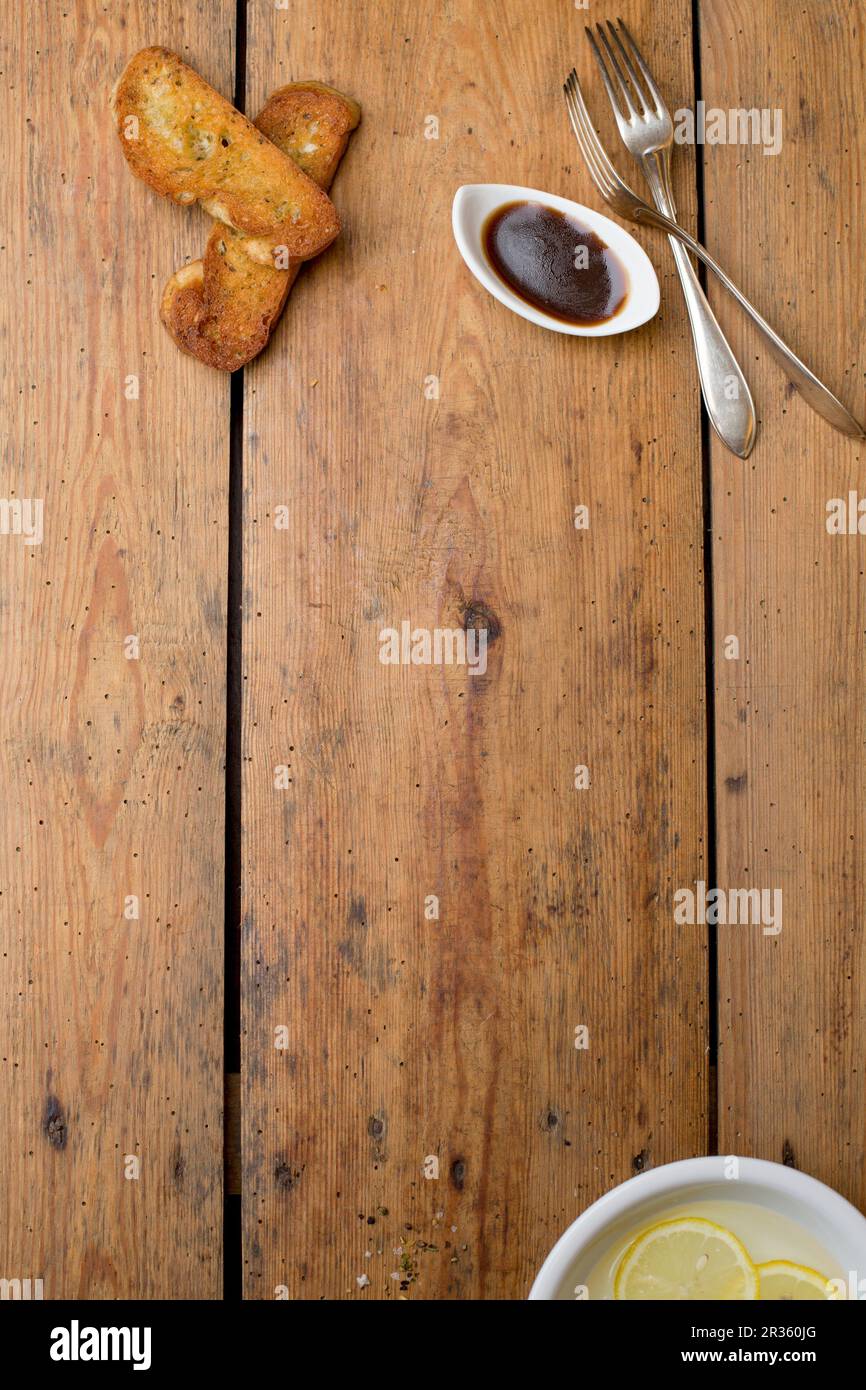 Scheiben gegrilltes Brot und eine Schüssel Balsamico-Dressing auf einem Holztisch Stockfoto