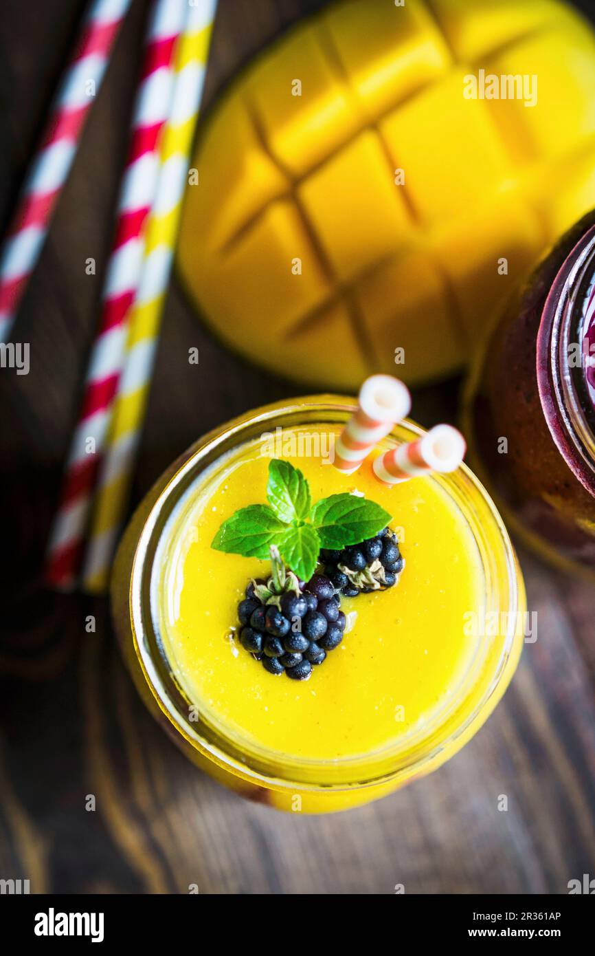 Mehrlagiger Mango- und Beeren-Smoothie garniert mit Brombeeren Stockfoto