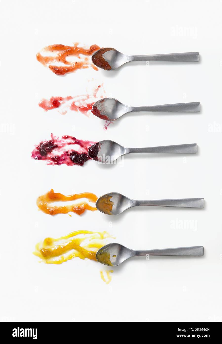 Fünf verschiedene Marmeladen auf Löffeln auf einer weißen Oberfläche Stockfoto