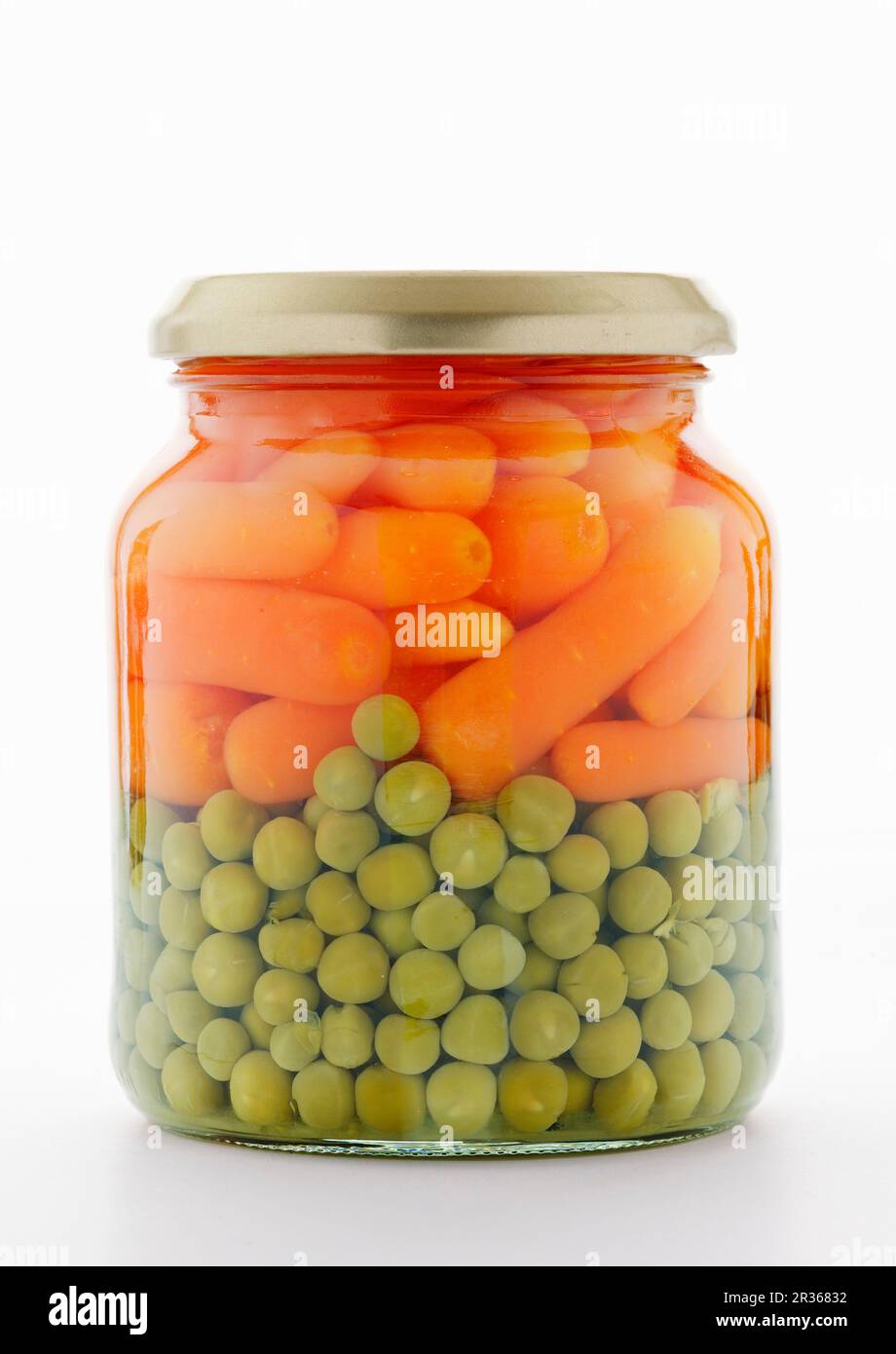 Erbsen und Karotten in einem Glas auf einer weißen Oberfläche Stockfoto
