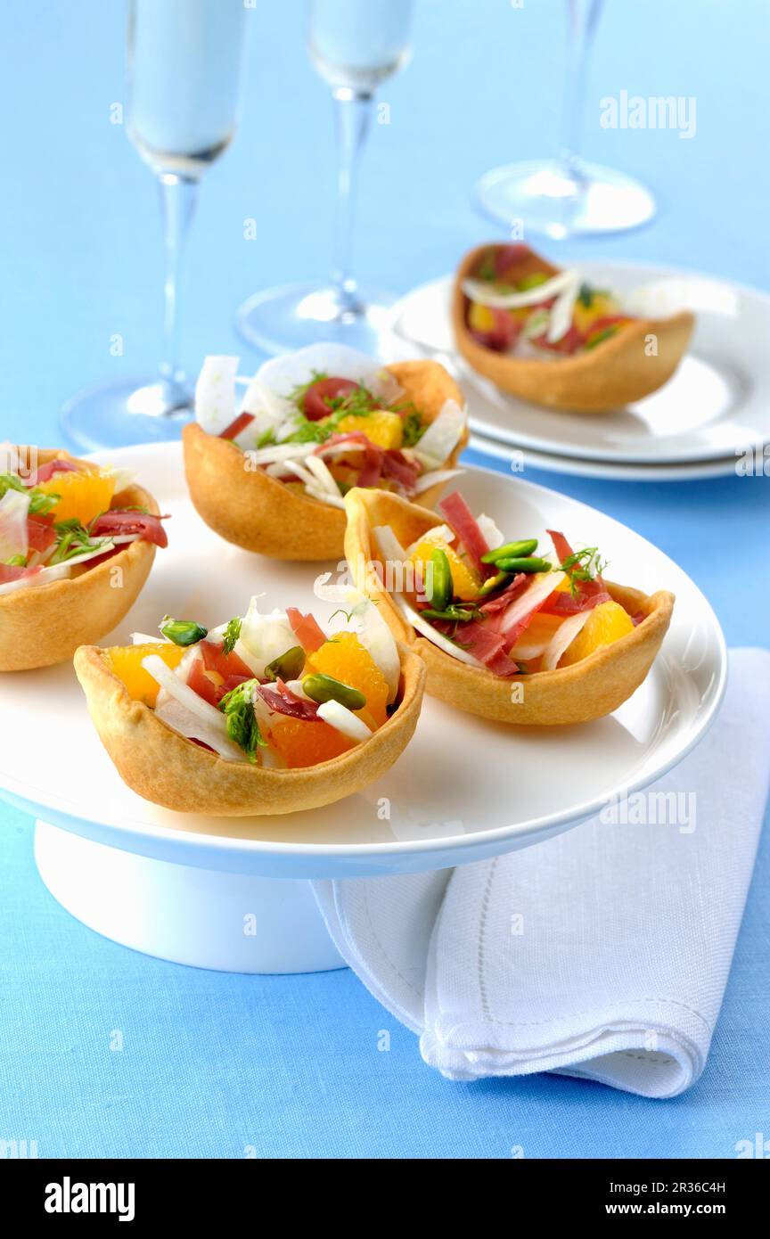 Backschalen gefüllt mit Prosciutto, Grapefruit und Gemüse Stockfoto