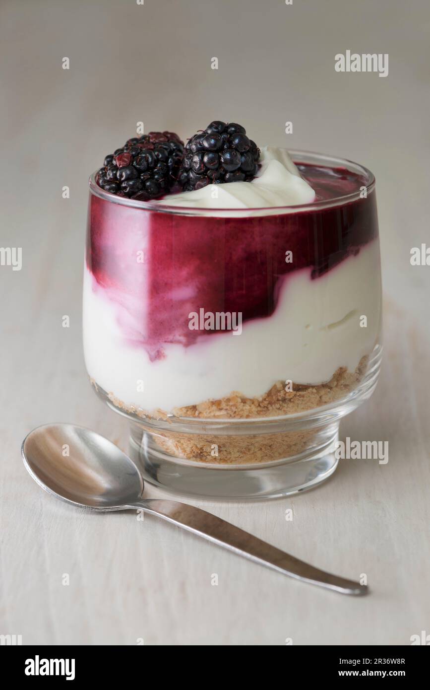 Blackberry cheesecake gemacht withcream Käse, Sahne, black Coulis und zerdrückten Kekse in einem Glas serviert. Stockfoto
